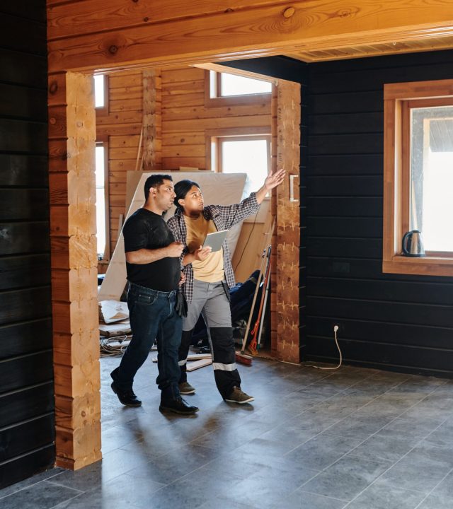 Two adults discussing home renovation in a partially constructed modern wooden interior.